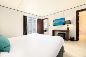 a bedroom with a white bed and a desk at Sonesta Maho Beach All Inclusive Resort Casino & Spa in Maho Reef