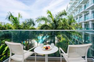 d'une table et de chaises sur un balcon avec des palmiers. dans l'établissement Sonesta Maho Beach All Inclusive Resort Casino & Spa, à Maho Reef