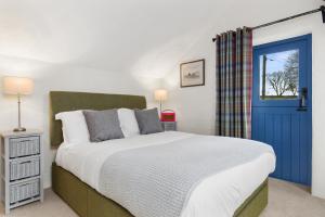 - une chambre avec un grand lit et une porte bleue dans l'établissement Preseli Hills Cottages - Luxury 5 star Cottages in Pembrokeshire, à Mynachlogddu