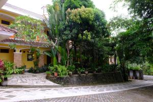 a courtyard with trees and plants in front of a building at Villa Alicia - Pavillion Lily in Yogyakarta