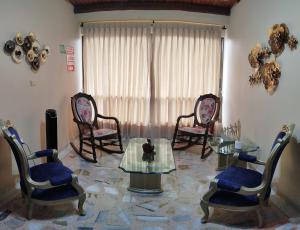 a living room with chairs and a glass table at Hotel Casa Aragon in Cartago