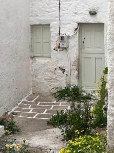 a white building with a door and some flowers at Sunset House in Serifos Chora