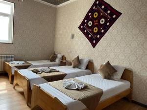 a room with three beds and a chandelier on the wall at Polvon Ota Hotel in Khiva