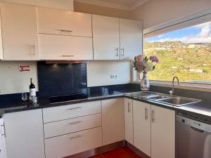 a kitchen with white cabinets and a sink and a window at Aylevarroo Penthouse in Caniço