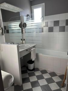 a white bathroom with a sink and a tub at Hôtel Le Boïate in Arès