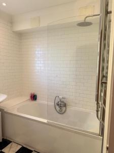 a bath tub in a bathroom with white tiles at Palm Bay Residency in Cliftonville +40 photos