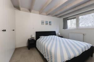 Schlafzimmer mit einem Bett mit gestreifter Decke in der Unterkunft Boszicht Huisje 32 in Nieuwmunster