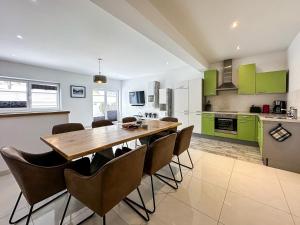 eine Küche mit grünen Schränken sowie einem Holztisch und Stühlen in der Unterkunft Ours Living Hohe Tauern - inkl Sauna in Hollersbach im Pinzgau + 8 Fotos