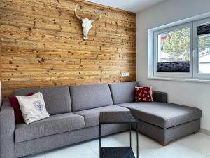 ein Wohnzimmer mit einem Sofa und einer Holzwand in der Unterkunft Ours Living Hohe Tauern - inkl Sauna in Hollersbach im Pinzgau