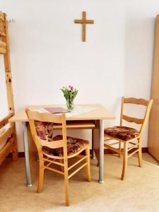 Die Malche Gäste und Tagungshaus 17 في Malche: طاولة مع كرسيين وصليب على الحائط