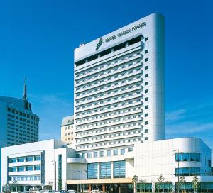 un gran edificio de hotel blanco con coches aparcados frente a él en Hotel Green Tower Makuhari, en Chiba