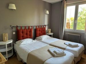 a bedroom with two beds with towels on them at Hôtel Le Boïate in Arès