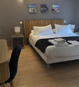 a bedroom with a large bed and a chair at Hôtel Le Boïate in Arès