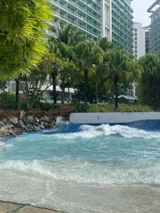 a river with waves and palm trees and buildings at The Bahamas & Maldives Suites at Azure Residences near Manila Airport in Manila