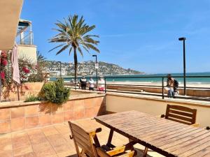 a wooden table and chairs next to the beach at Apartamentos Stella Maris in Roses