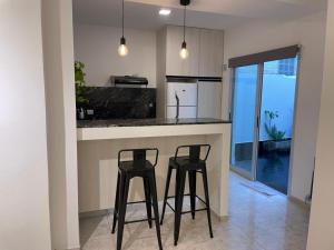 a kitchen with two black stools at a counter at Torre Kalinka dos dormitorios pleno centro 6 personas in Villa Carlos Paz