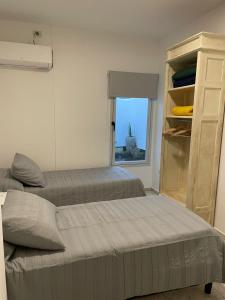 two beds in a room with a window at Torre Kalinka dos dormitorios pleno centro 6 personas in Villa Carlos Paz