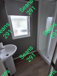 a bathroom with a toilet and a sink and a window at Seans 291 sandy cove 041 in Barmouth