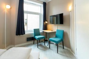 a room with a bed and a table and two blue chairs at Pensjonat Jarlen in Trondheim