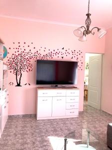 a living room with a tv and a tree with birds at Gemütliche Ferienwohnung zwischen Bergen und Meer in Orizare