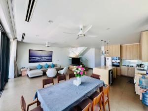 eine Küche und ein Wohnzimmer mit einem Tisch und einer Couch in der Unterkunft Beachfront 4 Bedrooms private pool villa Sanctuary Ho Tram resort in Hồ Tràm