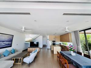 ein Wohn- und Esszimmer mit einer Couch und einem Tisch in der Unterkunft Beachfront 4 Bedrooms private pool villa Sanctuary Ho Tram resort in Hồ Tràm