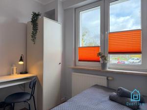a bedroom with a bed and a desk and two windows at Spongebob Room 10 Min to Old Town Gdańsk,PKP & Shopping Mall in Gdańsk