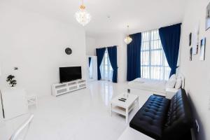 a white living room with a couch and a tv at MK Residence JVC in Dubai