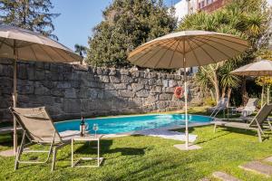 a swimming pool with two chairs and two umbrellas at Aparthotel Oporto Alves da Veiga in Porto