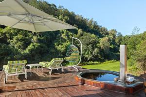 a patio with two chairs and an umbrella and a pool at Amazing Riverside Retreat with Hot Tub & EcoPool in Mossel Bay