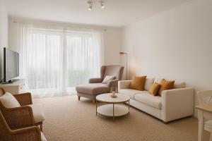 een woonkamer met een bank, stoelen en een tv bij Ferienwohnung Meeresrauschen in Schausende