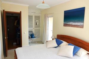 a bedroom with a bed with blue and white pillows at Aylevarroo Penthouse in Caniço