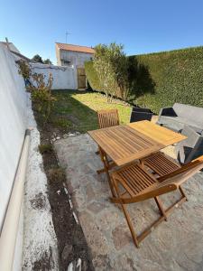 Una mesa y sillas de madera en un patio. en Maison tout confort 4 personnes port des salines 3 étoiles 2025, en Grand-Village-Plage 1 foto más