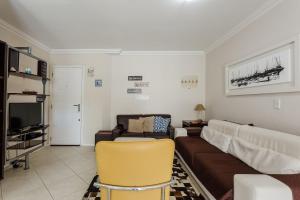 a living room with a couch and a tv at Apto espaçoso com piscina em Jurerê | CHR025 in Florianópolis