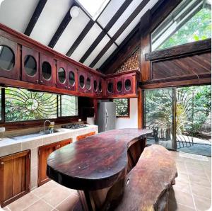 a kitchen with a large wooden table and some windows at La Casa Del Sol in Hone Creek
