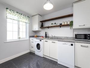 una cocina con gabinetes blancos y una lavadora y secadora en Family Friendly- 3 Bed House For 5-City Central - Free Parking, en Kent