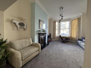 a living room with a couch and a chair at 4 Queens Gardens Seaside Apartment in Eastbourne