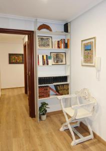 a white chair in a room with a book shelf at Apartamento Victoria in Valencia de Don Juan