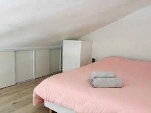 a bedroom with a pink bed with a pillow on it at Duplex cosy neuf - wifi - balcon - en bordure de forêt de pins - proche plage in Saint-Jean-de-Monts