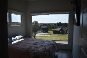 a bedroom with a bed and a large window at Cabañas alto Volcanes, Puerto Montt in Puerto Montt