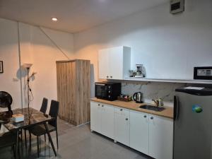 a kitchen with white cabinets and a table and a refrigerator at Dorothys in Pattaya South
