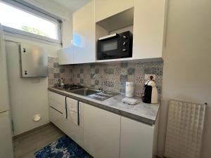a small kitchen with a sink and a microwave at Alloggio ampio zona San Martino in Sanremo