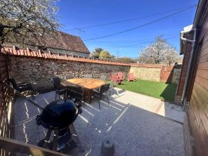 a patio with a table and chairs and a grill at La Ruche in La ForestiÃ¨re