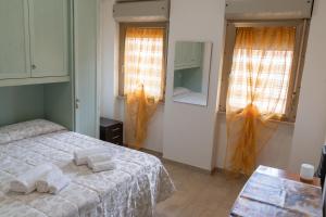 a bedroom with a bed and two windows and a table at Jungle House - Affitti Brevi Italia in Tarquinia