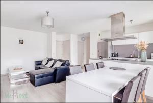 a kitchen and living room with a couch and a table at Perollier - CI - Lyon 2 - Bedroom apartment with balcony and pool in Écully