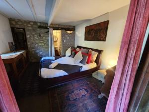 a bedroom with a bed with white sheets and red pillows at Stormsriver Backpackers - Dijembe in Stormsrivier