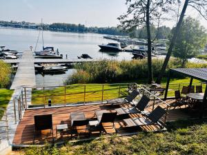 a wooden deck with chairs and a dock with boats at P R A T U M Pink&Blue Mikołajki Apartament Elegance z widokiem na jezioro in Mikołajki
