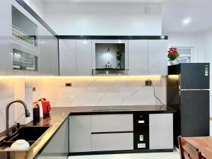 a kitchen with white cabinets and a black refrigerator at Hotel Kim Ngân Đảo Lý Sơn in Ly Son +34 photos