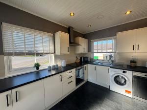 une cuisine avec des armoires blanches et une laveuse et une sécheuse dans l'établissement Eriskay cottage, Denholm, Scottish Borders, à Denholm