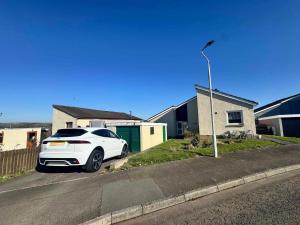 une voiture blanche garée sur le côté d'une rue dans l'établissement Eriskay cottage, Denholm, Scottish Borders, à Denholm